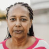 Senior african woman looking at camera outdoor in the city - Focus on face